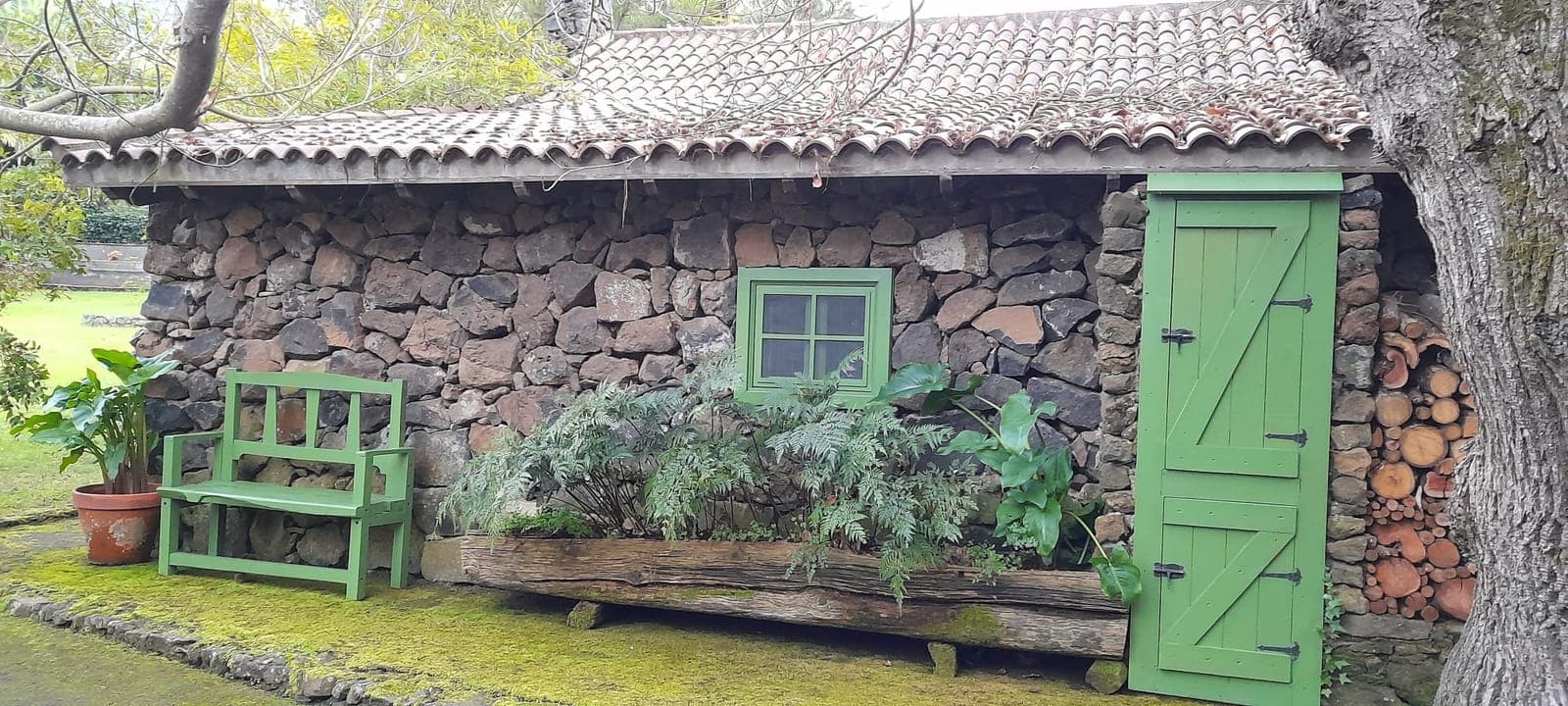 Pajar tradicional de piedra volcánica seca con puerta verde y tejado de paja
